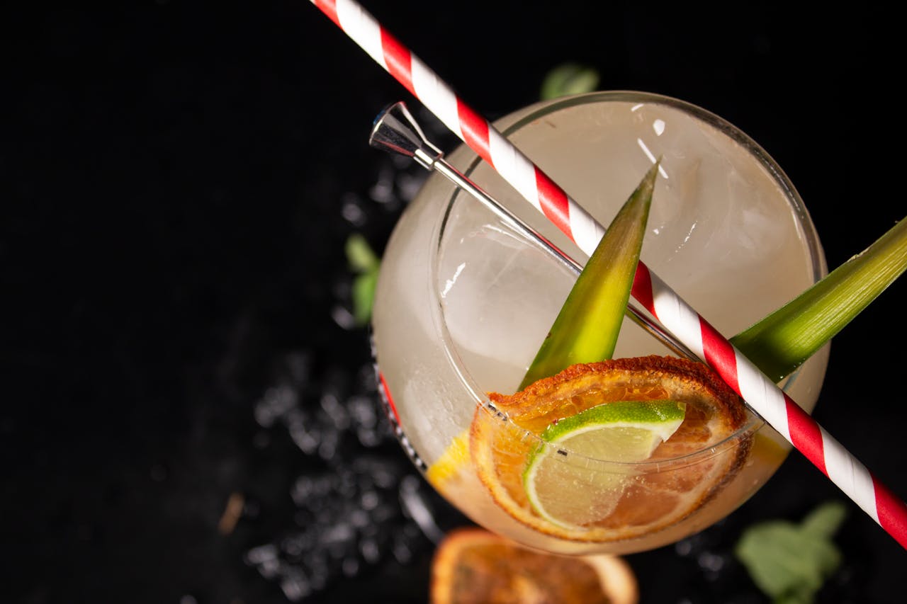Close-up of a colorful cocktail with citrus slices and tropical leaves, offering a fresh and cool refreshment.